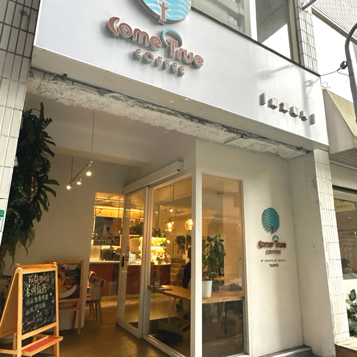 Vibe image of Come True Coffee 台北西門店: 雖然隱身巷弄，但店門口蠻顯眼的，裡面很多綠色植物（雖然都假的） shot by 阿波卡