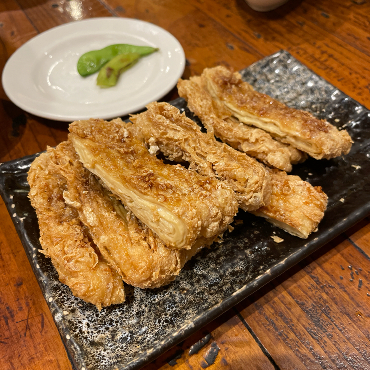 Meal image of 港町十三番地 雙十店: 烤豆皮
這是我們每次來必點的一項
豆皮烤得恰到好處，外面十分酥脆，搭配烤物的醬汁，真的會想再來一盤� shot by 一刻又一嗑