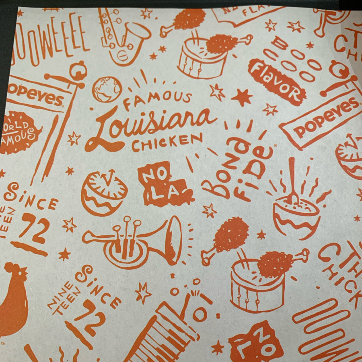 Vibe image of Popeyes Chicken 台北許昌店: 餐紙圖案很可愛，反映出店內音樂氣氛🎺 shot by Food Scouter